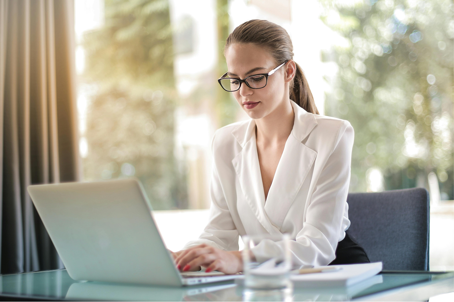 A professional woman working on a laptop in an office.